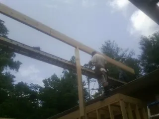 Carpenter setting a ridge beam over a new addition frame — Ice Dam Removal by Roofing Brothers in Eldora
