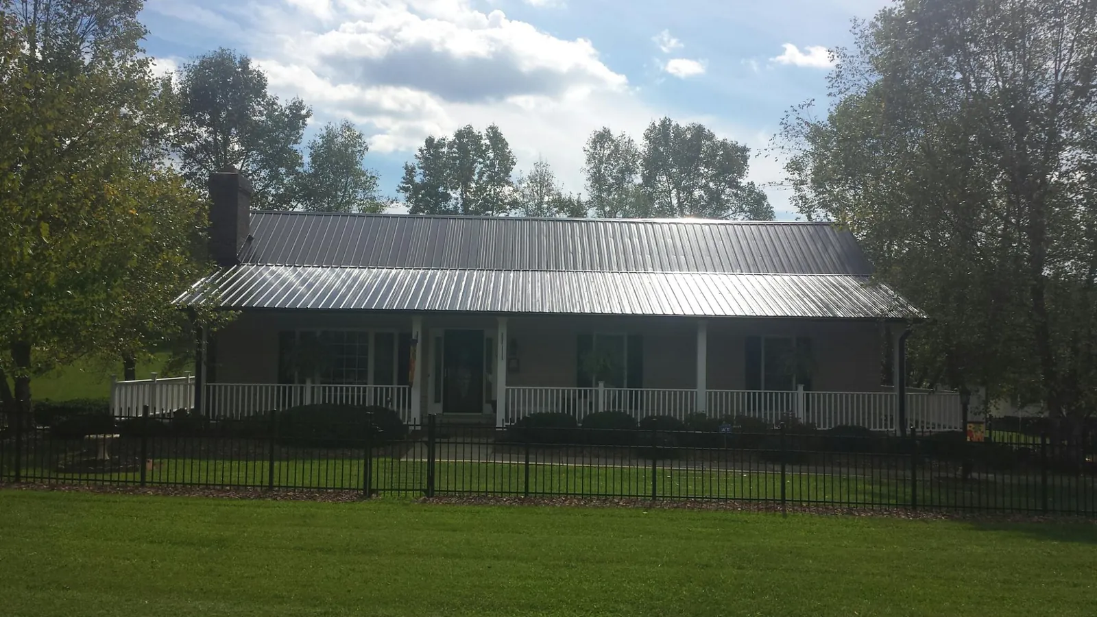 Gray metal roof on a brick ranch with a full width front porch — Gutter Guard Installation work by our crew in Eldora