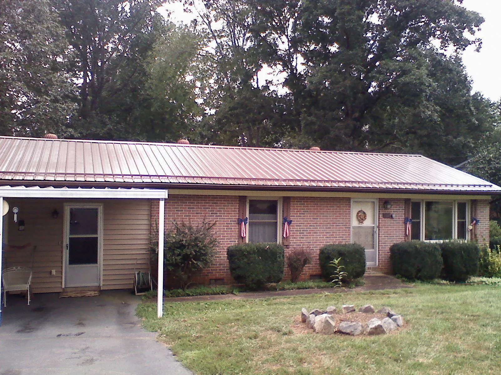 Bronze metal roof and carport on a brick ranch home — Roof Repair work by our crew in Eldora
