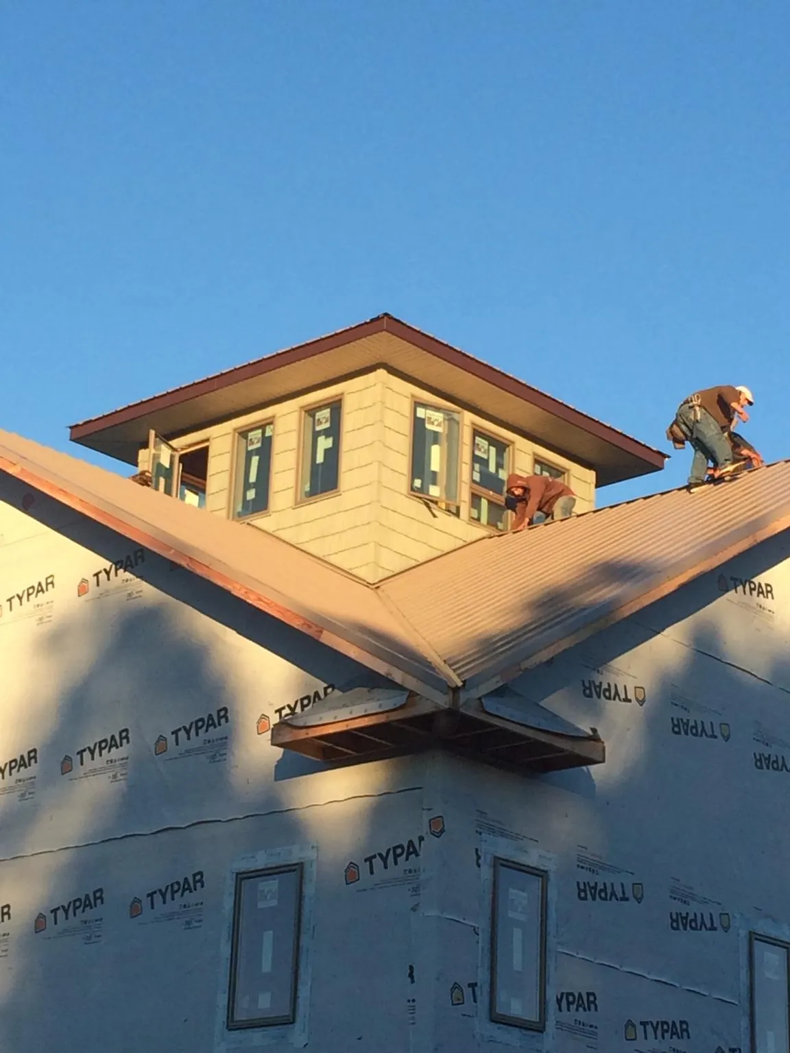 Roofers working around a rooftop cupola on a new metal roof at sunset — Roof Waterproofing in Eldora by Roofing Brothers